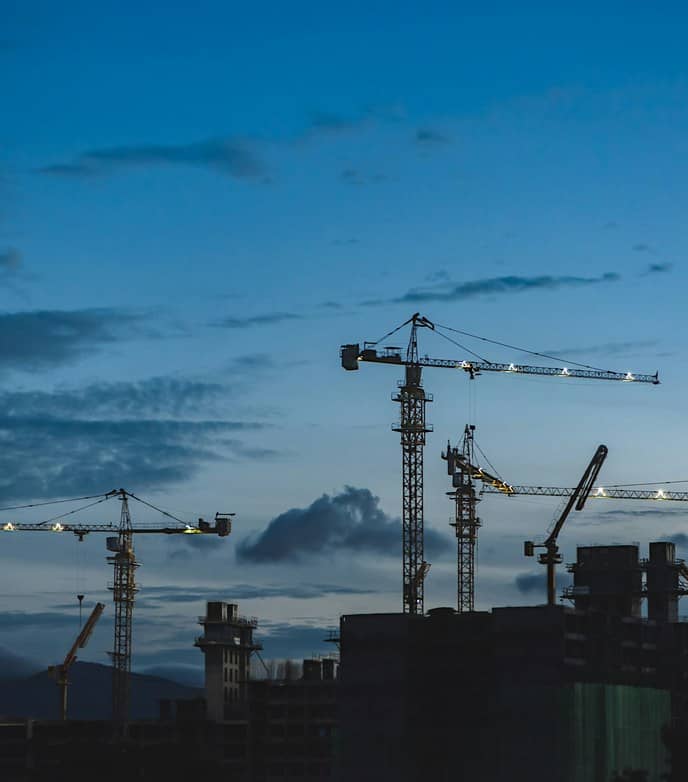 Baukräne auf einer Baustelle in der Abenddämmerung